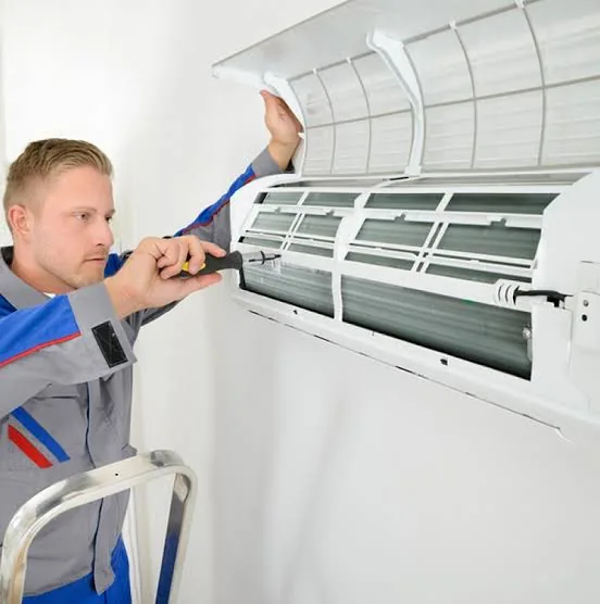 Technician servicing a wall-mounted air conditioner in a residential home