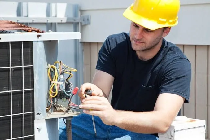 Technician diagnosing an outdoor air conditioning unit during an urgent service call