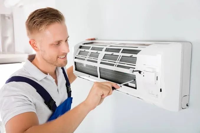 Technician inspecting an indoor wall-mounted heating and cooling unit