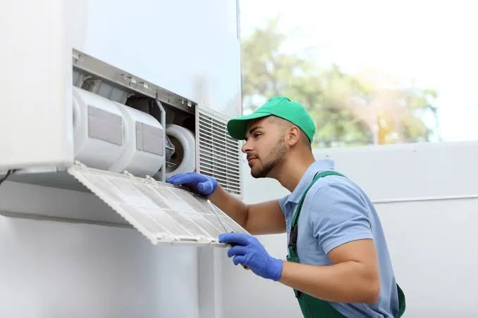 Technician removing a dirty HVAC filter during an indoor air-quality service visit