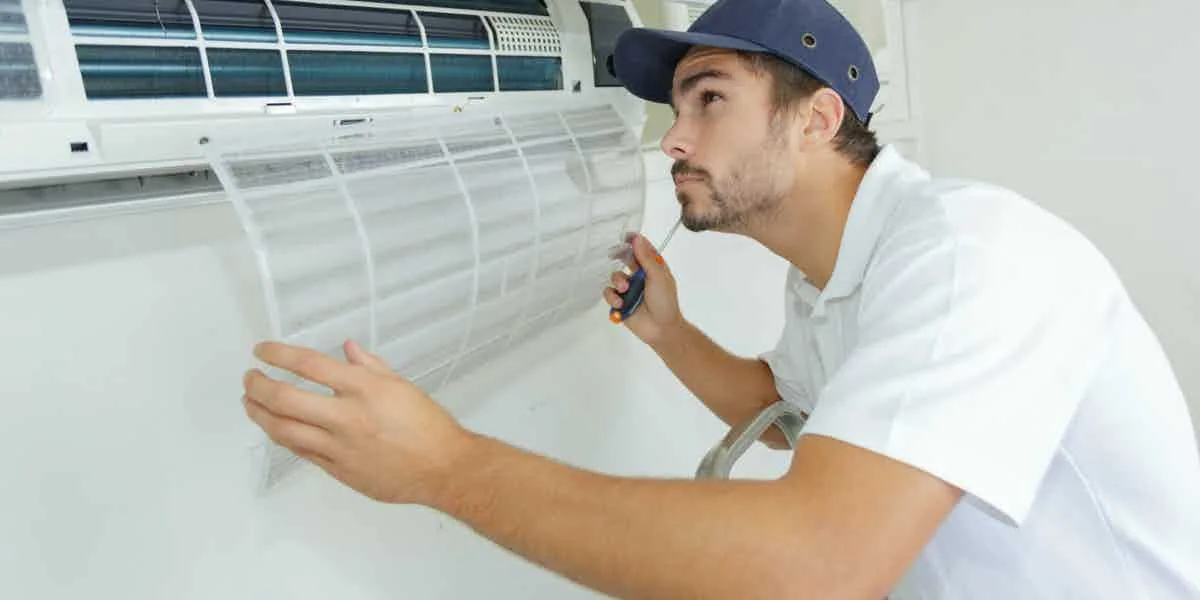Technician performing HVAC maintenance and filter service on a wall-mounted air conditioner